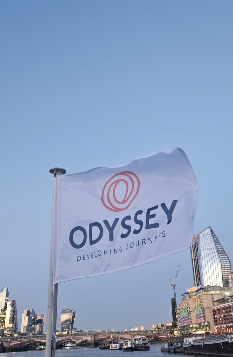 The Odyssey flag flying from the boat with the City of London skyline behind