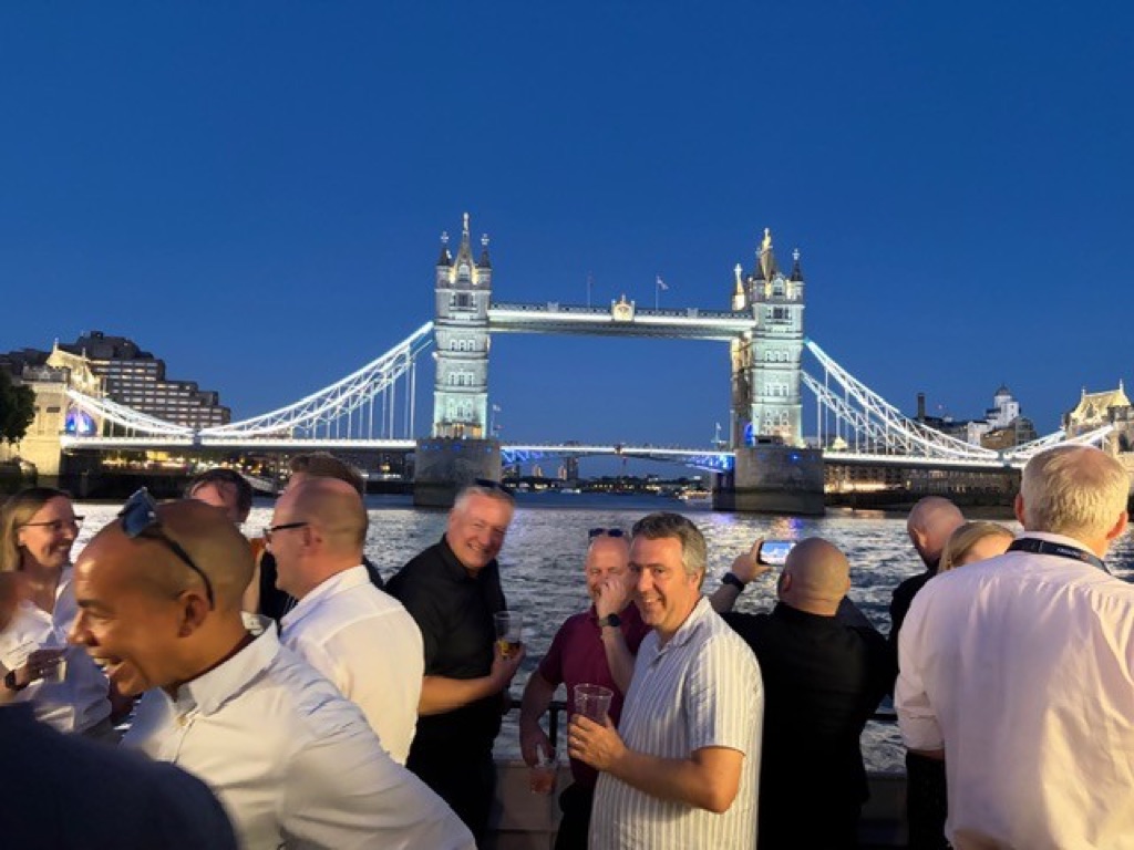 Guests on deck in the evening with Tower Bridge lit up behind them