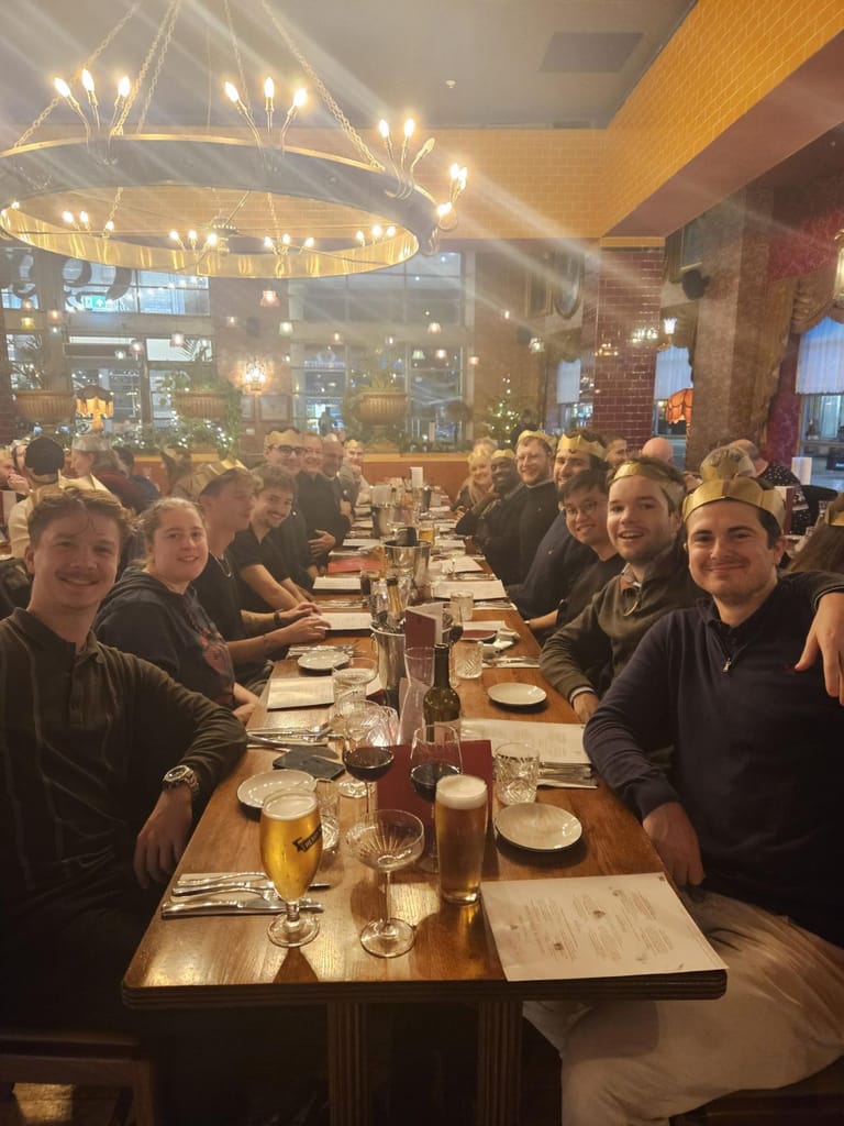 Colleagues at a long restaurant table under festive lights